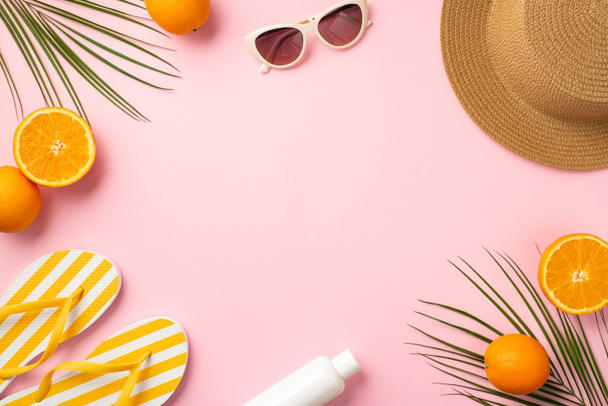 Summer holidays concept. Top view photo of sunhat sunglasses striped yellow slippers sunscreen bottle juicy oranges and palm leaves on isolated pastel pink background with copyspace in the middle - Фото, изображение