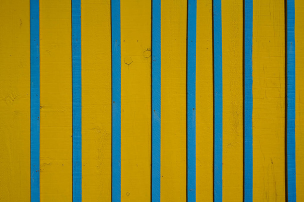 Vertical background wooden planks with cracked blue yellow paint - Foto, afbeelding