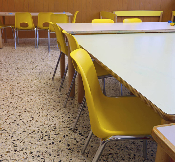 school classroom of a school with small yellow chairs and tables without children and without teachers - Photo, image
