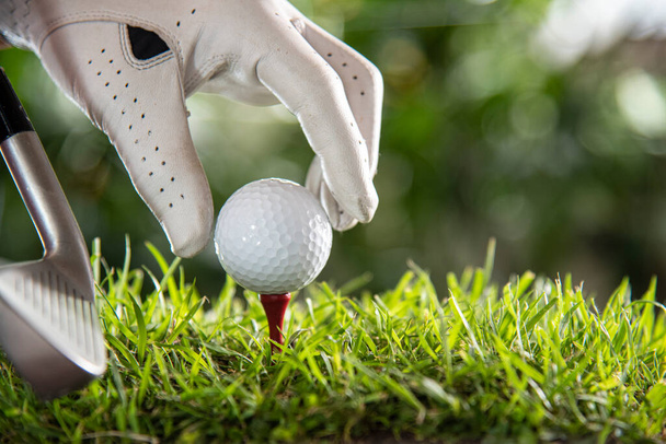 hand in golf glove put golf ball on red tee. - Foto, imagen