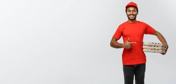 Delivery Concept - Portrait of Happy African American delivery man pointing hand to present a box package. Isolated on Grey studio Background. Copy Space. - Фото, изображение