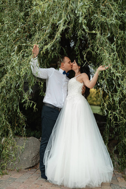 Glückliches Brautpaar nach der Trauung. Spaziergang im grünen botanischen Garten. - Foto, Bild