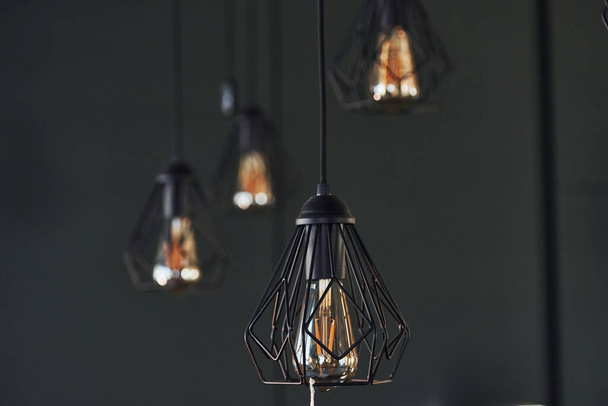 Modern designed light bulbs hangs on the wall indoors. Decoration and domestic life. - Φωτογραφία, εικόνα