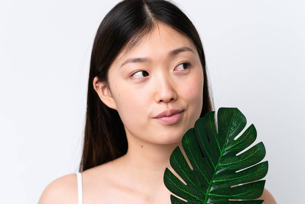 Young Chinese woman isolated on white background holding a palm leaf. Close up portrait - Foto, afbeelding