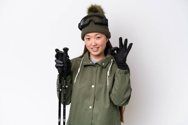 Jovem chinesa usando casaco de inverno isolado no fundo branco mostrando sinal ok com os dedos - Foto, Imagem