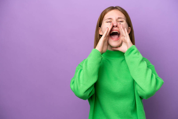 Nuori Englanti nainen eristetty violetti tausta huutaa ja ilmoittaa jotain - Valokuva, kuva