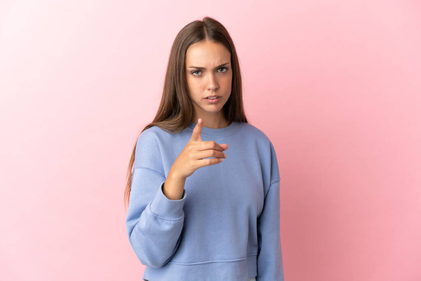 Young woman over isolated pink background frustrated and pointing to the front - Photo, Image