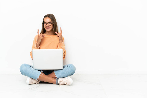 jonge vrouw met een laptop zitten op de vloer wijzend op een geweldig idee - Foto, afbeelding