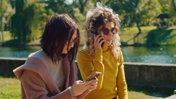 dos chicas felices charlando usando el teléfono. disfrutando del tiempo juntos. días de verano. - Metraje, vídeo