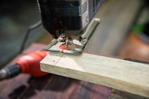 carpenter using jigsaw cutting wood - Foto, afbeelding