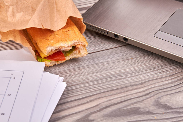 Sandwich and laptop on the office desk. - Foto, imagen