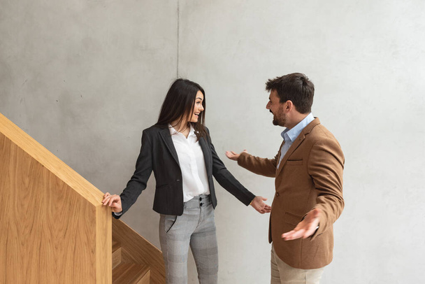 Young business people met on the staircases in the office building woman congratulates man colleague on job promotion. Successful happy workers talking not seeing long tame when she is promoted. - Foto, Imagen