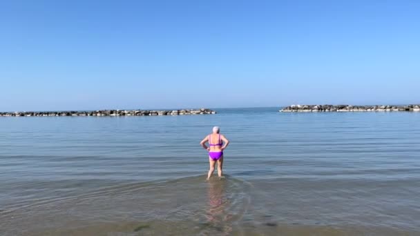 Adriatic Riviera. Elderly woman walking in the sea.  - Záběry, video