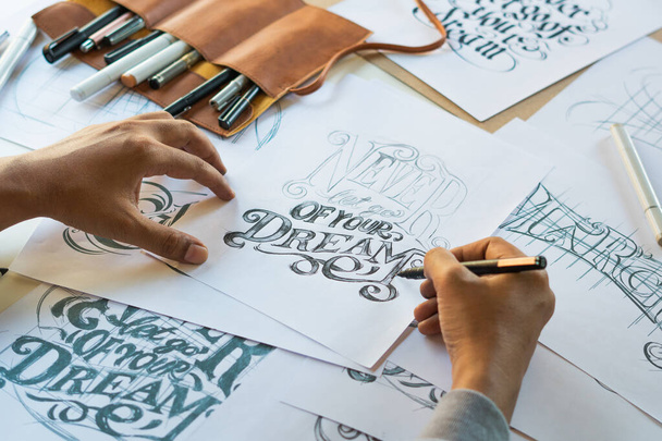 Typography Calligraphy artist designer drawing sketch writes letting spelled pen brush ink paper table artwork.Workplace design studio. - Photo, Image