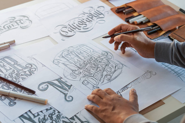Tipográfia Kalligráfia művész tervező rajz vázlat írja hagyta betűzött toll ecset tinta papír asztali műalkotás.Munkahelyi design stúdió. - Fotó, kép