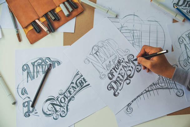 Typography Calligraphy artist designer drawing sketch writes letting spelled pen brush ink paper table artwork.Workplace design studio. - Fotografie, Obrázek