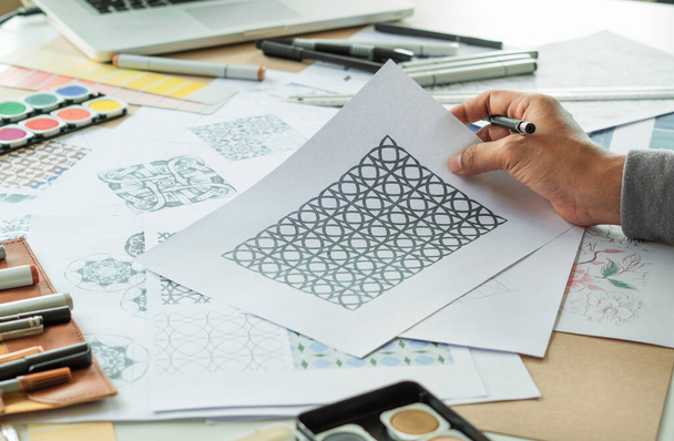 Designer designing drawing sketch pattern geometric flower seamless wallpaper fabric textile fashion industry. artistic design studio - Fotó, kép