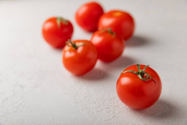 Свіжі червоні помідори на тлі сірої текстури. Вишневі помідори з зеленими стеблами. Свіжі овочі. Місце для копіювання
. - Фото, зображення
