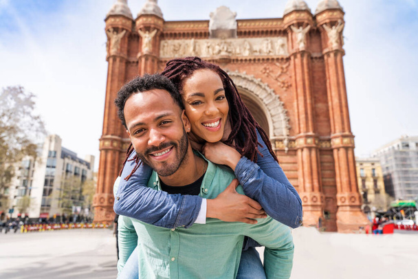 Beautiful happy hispanic latino couple of lovers dating outdoors - Tourists in Barcelona having fun during summer vacation and visiting Arc de Triumf historic landmark - Фото, изображение