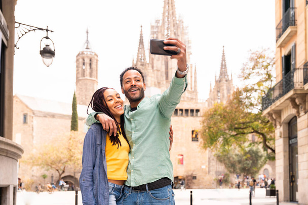 Beautiful happy hispanic latino couple of lovers dating outdoors - Tourists in Barcelona having fun during summer vacation and visiting Barcelona Cathedral historic landmark - Foto, afbeelding