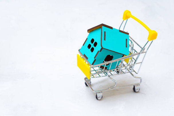 Plywood toy house model in a miniature shopping trolley with copy space. Buying prefab home. - Фото, зображення