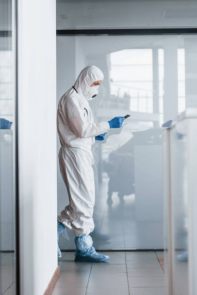 Male doctor scientist in lab coat, defensive eyewear and mask holding notepad in hands. - Foto, afbeelding
