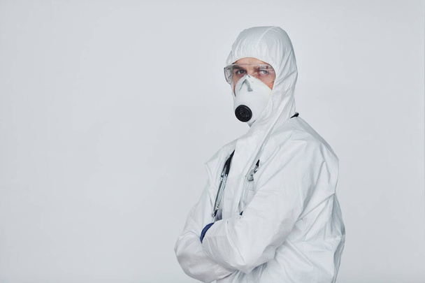 Male doctor scientist in lab coat, defensive eyewear and mask standing against white background. - Foto, imagen