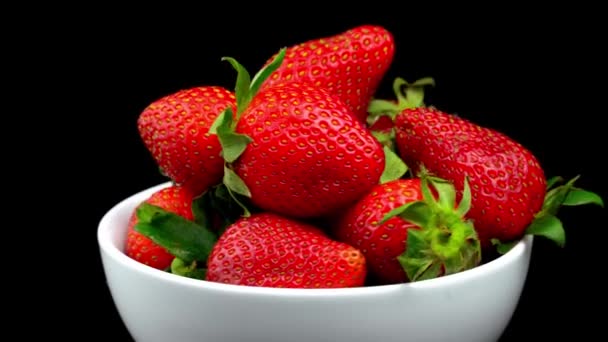 Appetizing strawberries with wilted green leaves lie on white porcelain bowl - Filmagem, Vídeo