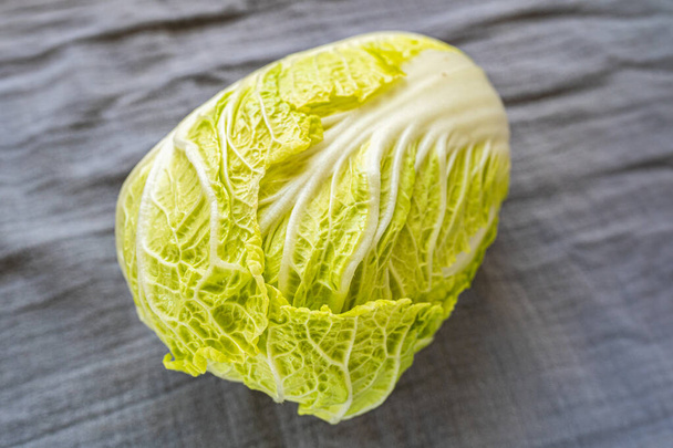 Fresh cabbage with juicy leaves close up top view. Chinese cabbage Napa cabbage on fabric background with shadow in natural light - Foto, Imagen