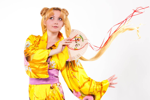 Beautiful young blonde. Young blonde woman in a yellow kimono, with a fan in her hands, isolated on a white background. - Foto, Imagem