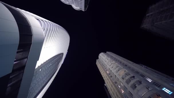 Камера вращается по кругу с видом на высокие небоскребы ночью - Кадры, видео