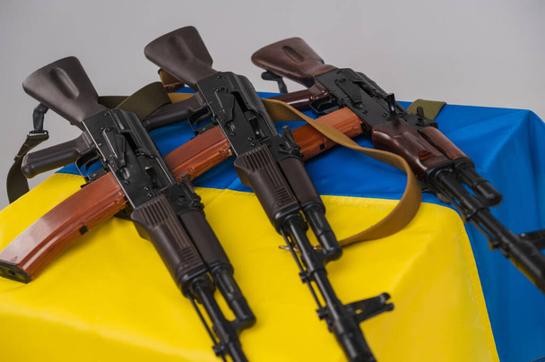 Three loaded Kalashnikov 74 assault rifles on the blue and yellow flag of Ukraine - Photo, image