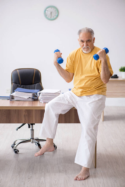 Old businessman employee doing sport exercises in the office - Foto, Bild