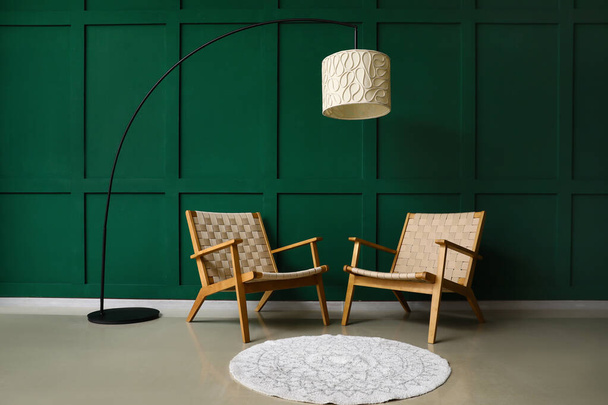 Stylish armchairs and lamp near green wall - 写真・画像