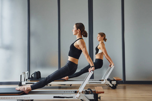 Hands strength. Two women in sportive wear and with slim bodies have fitness yoga day indoors together. - Foto, Imagem
