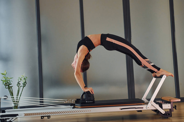 Young woman in sportive wear and with slim body have fitness yoga day indoors. - Foto, afbeelding