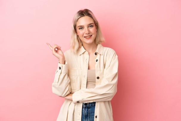 Young caucasian woman isolated on pink background happy and pointing up - Foto, afbeelding