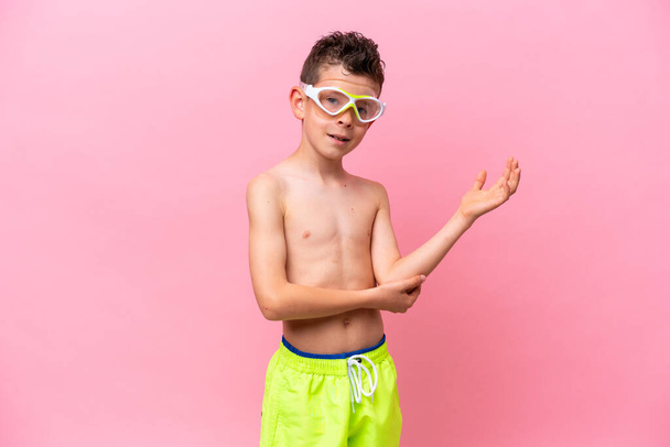 Petit garçon caucasien portant un masque de plongée isolé sur fond rose étendant les mains sur le côté pour inviter à venir - Photo, image