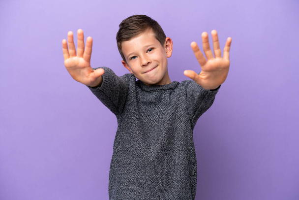 Little boy isolated on purple background counting ten with fingers - Valokuva, kuva