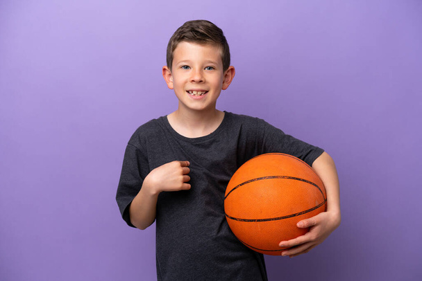 Kleine jongen spelen basketbal geïsoleerd op paarse achtergrond met verrassing gezichtsuitdrukking - Foto, afbeelding