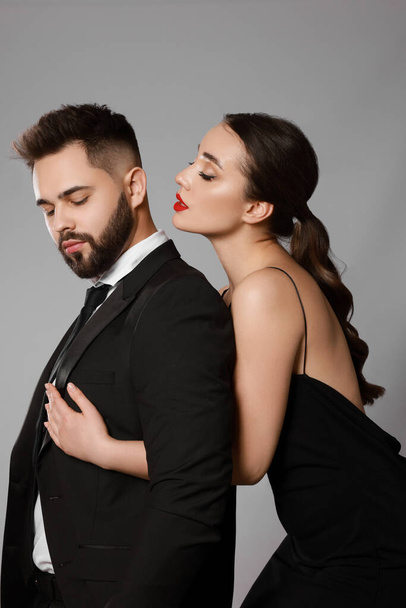 Handsome bearded man with sexy lady on grey background - Foto, afbeelding