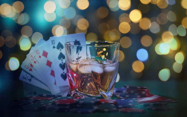 Casino chips, cards and alcohol drink on table against blurred lights. Straight poker combination - 写真・画像