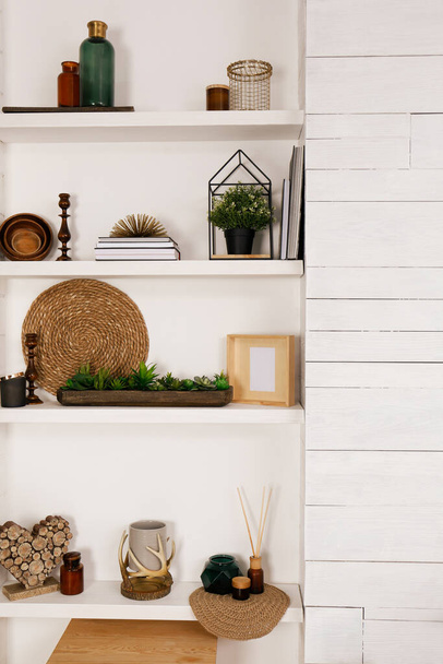Wall shelves with beautiful decor elements indoors. Interior design - 写真・画像