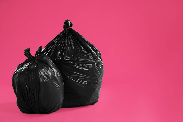 Trash bags full of garbage on pink background. Space for text - Fotó, kép