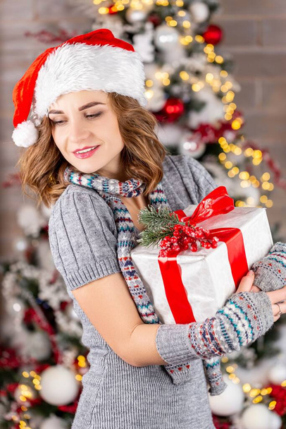 Женщина с подарком в руках в платье, шарфе и Санта ха - Фото, изображение