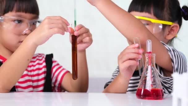 Дети учатся и проводят научные эксперименты в классе. Две младшие сестры играют в научный эксперимент для домашнего обучения. Простые и веселые научные эксперименты для детей дома. - Кадры, видео