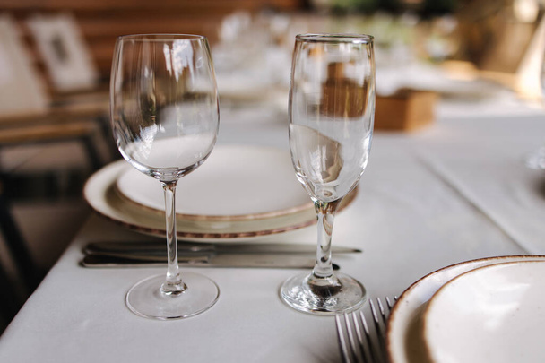 Asztalbeállítás, gyönyörű fehér tányérok, ezüst evőeszközök és kristálypoharak. Szabadtéri lakoma vakáción. Parti - Fotó, kép
