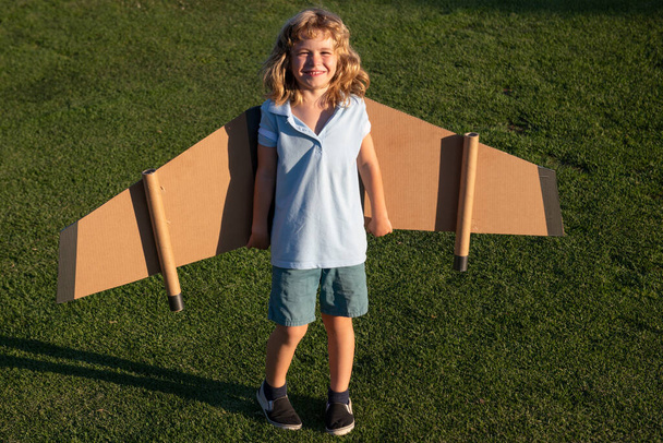 Cute dreamer boy playing with a cardboard airplane. Childhood. Fantasy, imagination. - Zdjęcie, obraz