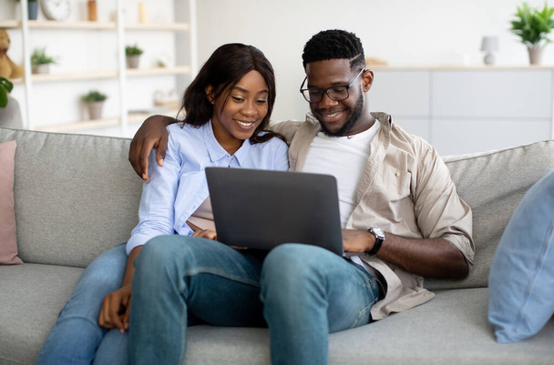 Retrato de pareja afroamericana usando laptop en casa - Foto, Imagen