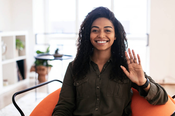 Greeting Concept. Smiling black woman waving hand at camera - Foto, afbeelding
